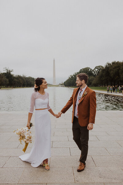Bride and Groom hold hands in front of washington monument