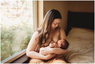 Mother breastfeeding newborn baby bathed in golden light