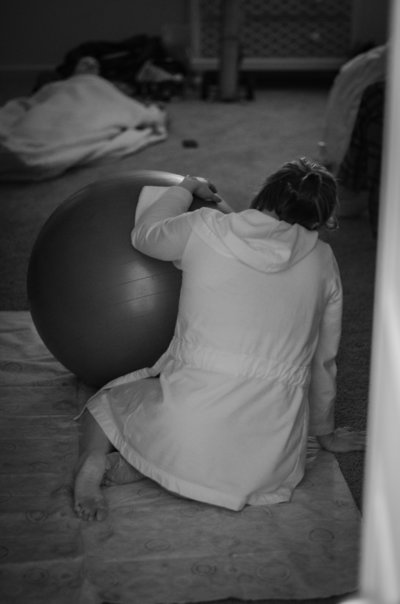 Mother in labor rests her hands on birthing ball during labor