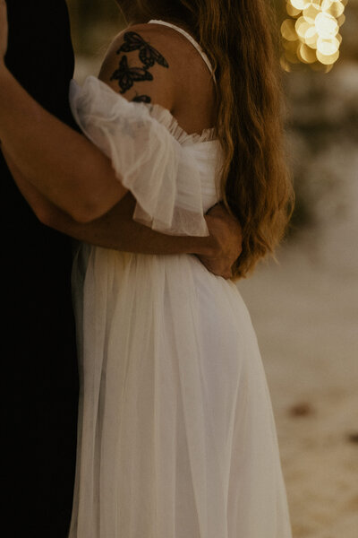 A close up photo of a man's hand on his wife's waist