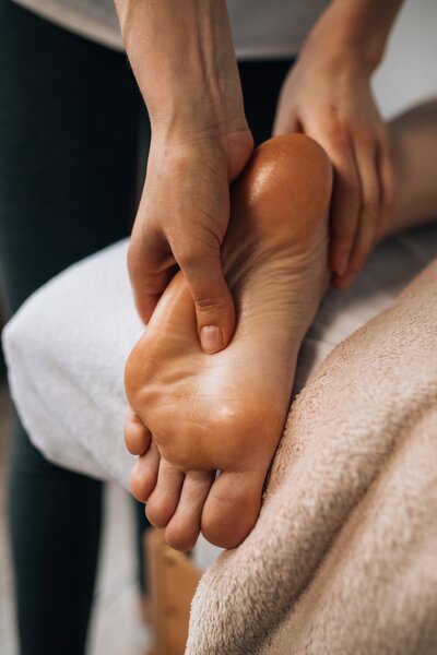 A massage therapist working on a clients foot to relieve pain