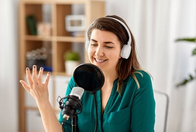 Happy woman podcaster wearing headphones speaking in a microphone