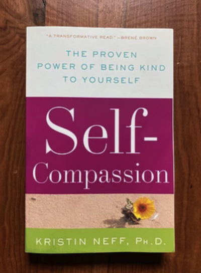 Self Compassion book sitting on a wood table