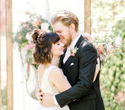 Bride and groom hugging in front of floral backdrop