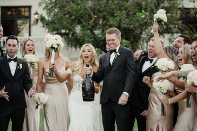 bridal party pops a huge bottle of champagne  captured by los angeles wedding photographer magnolia west photography