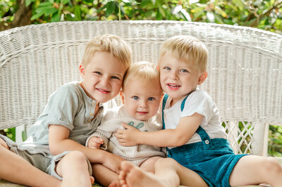 York PA family photographer captures two brothers smiling on a wicker bench during an outdoor session