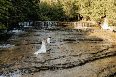 bride and groom walking in a cascading waterfall