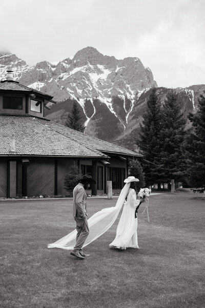 Bride and groom walking across an alpine meadow at Boundary Ranch surrounded by the Rocky Mountains during a Banff wedding weekend — cinematic, story-led destination photography.