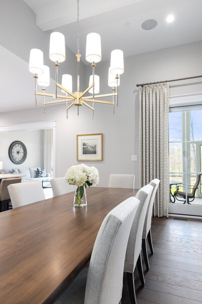 Dark wood dining table with chairs and flowers and bright lighting feature