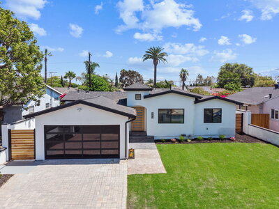Front view of a fully renovated modern home in Los Angeles with black trim, paver driveway, and landscaped front yard—prepped for sale by AW Development Co.