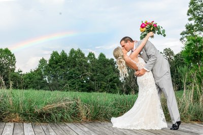 Groom Kissing Bride with Rainbow in Sky