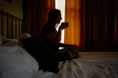 Woman Sitting on Bed Drinking Coffee