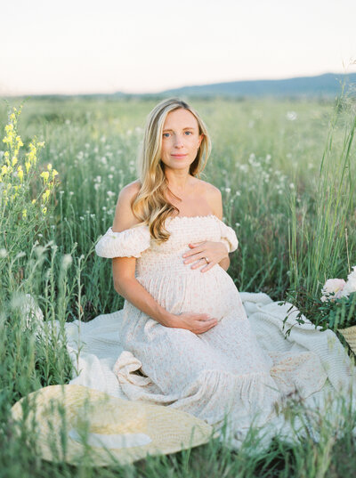 Maternity photography featuring mom to be sitting in a field.