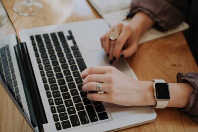 the hands of a woman on a laptop keyboard