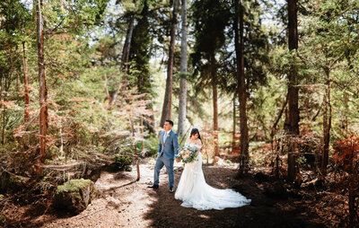 bride and groom posing in front of trees and greenery in silverthorne co