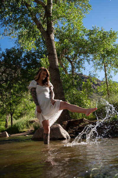 Portrait of a woman splashing in the river in a beautiful sundress.