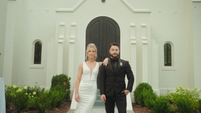 The couple in wedding attire embraces near a vintage car in nature. Capturing romantic moments on their special day.
