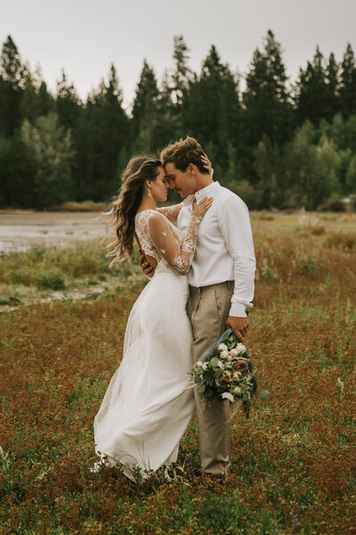 Bride and Groom holding each other close with foreheads touching and bride touching groom's chest in a field surrounded by trees in Lake Tahoe by California Elopement Photographer Kasey Mantiply