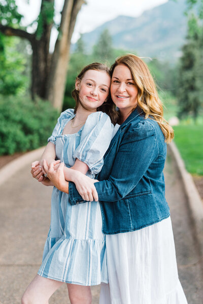mom hugging teenage daughter from behind and smiling at camera during family photo session with Colorado Springs photographer Erin Winter