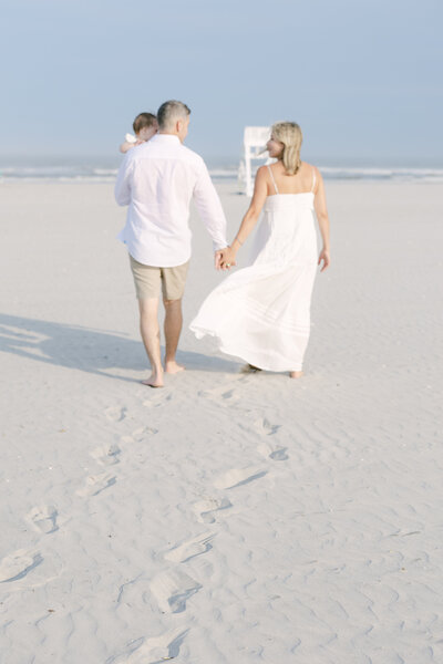 A family walks hand in hand on a sandy beach