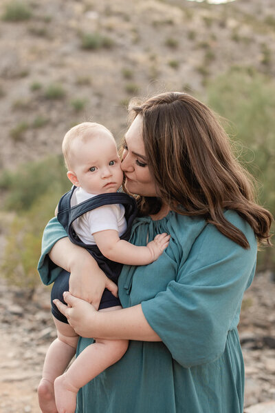 Mom kises her 1 year old son while holding him in her arms
