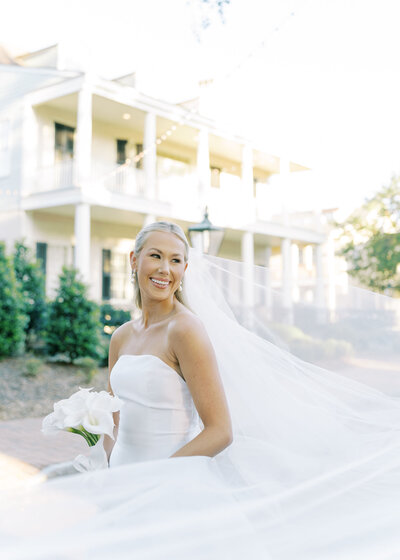 a bride smiling in a wedding dress and veil