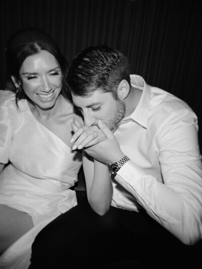 A groom kisses his bride's hand at their Shinola Hotel wedding reception, bride in short second dress, bride reception dress