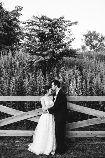 bride and groom embrace along a fence ohio wedding