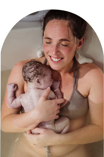 holding baby in the birth tub with the umbilical cord still connected