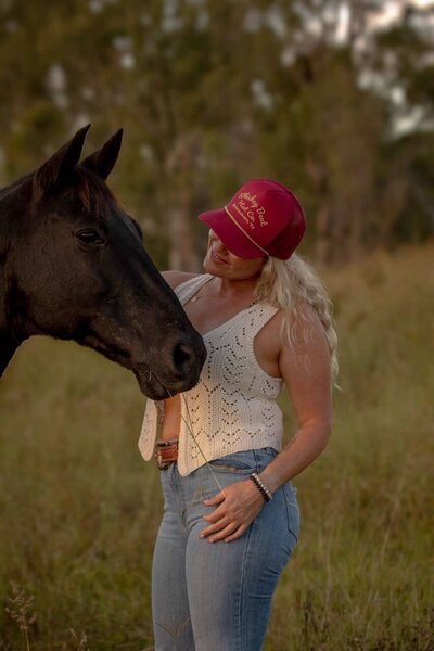 Woman in red hat connecting with a equine during a horse retreat in Australia. 