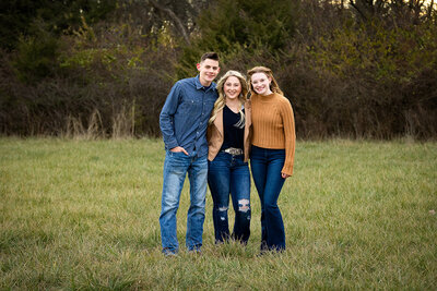 siblings hugging in a field