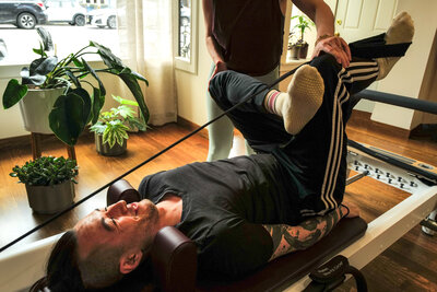 Man lying in the figure four position on a reformer during a private session at Craft Pilates