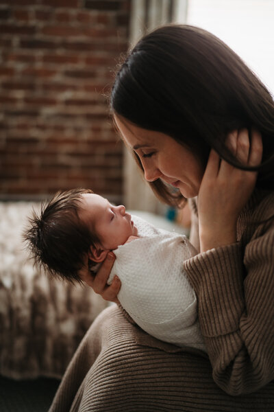 mom holding newborn in boston window