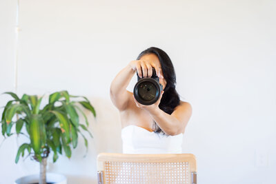 Dallas personal brand photographer posing with her professional camera inside her natural light photo studio