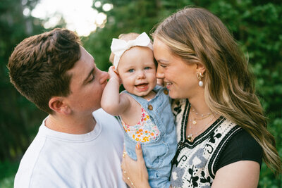 Magnolia Smiling with her parents kissing her
