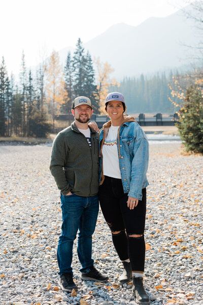 Couple standing on pebble beach in Banff Alberta smiling