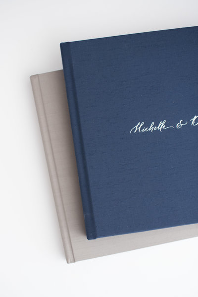 Elegant custom engagement photo albums in navy blue and taupe linen covers — offered by Charlotte’s top-rated proposal photographer DeLong Photography.