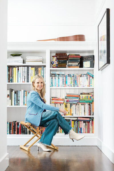 Interior Designer posing in front of a bookshelf for her brand photoshoot.