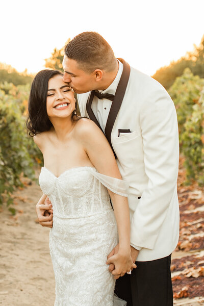 WEDDING OUPLE IN VINEYARD KISSING HEAD