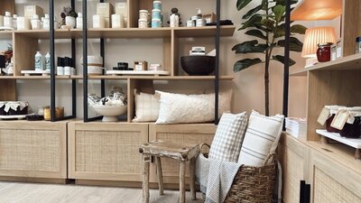 interior shot of The Still Refinery mercantile with stocked shelves full of skincare, pillows, candles and a pretty tree in the corner next to a warm lamp