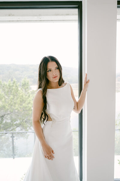 Austin wedding photographer captures bride in modern gown by large window at The Videre Estate wedding venue.