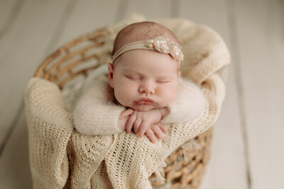 baby girl in basket prop hwrapped in white