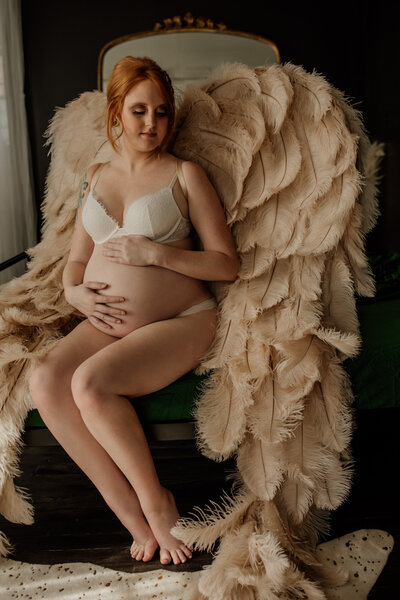 pregnant woman sitting on bed holding her belly