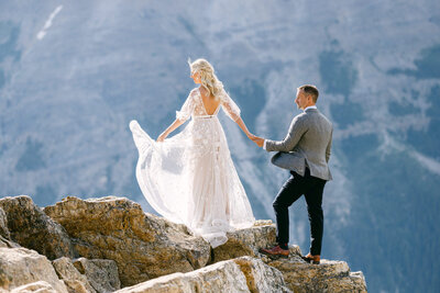 This captivating portrait features the bride and groom walking up the rocks at Peyto Lake in Banff National Park. The dramatic landscape and turquoise waters create an unforgettable setting, showcasing the couple's adventurous spirit on their special day.