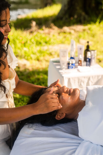 Woman giving someone a facial outdoors