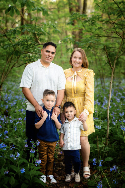 A family of six standing in the fall foliage smiling and embracing each other.
