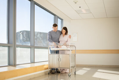 Mom and dad standing by bassinet in hospital