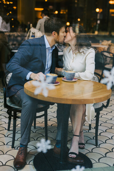 An engagement photo captured through the window of a coffee shop.