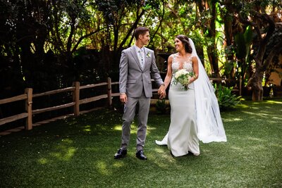 Bride and groom laughing and holding hands amid the nature at Green Gables Wedding Estate wedding venue in San Marcos.