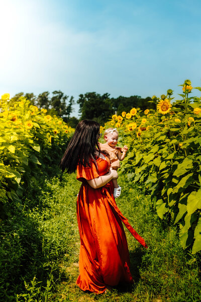 Mommy and baby playing in the sunflowers